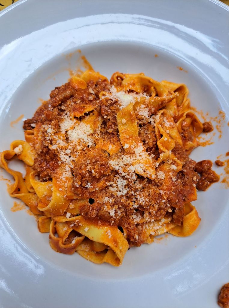 I'm Sofia Lena Perissinotto. I am a travel blogger. In this blog post I talk about Bologna, a stunning, historical city located in the Italian region Emilia-Romagna. In this photo you can see a photo from a delicious food plate. It's handmade tagliatelle with ragù!