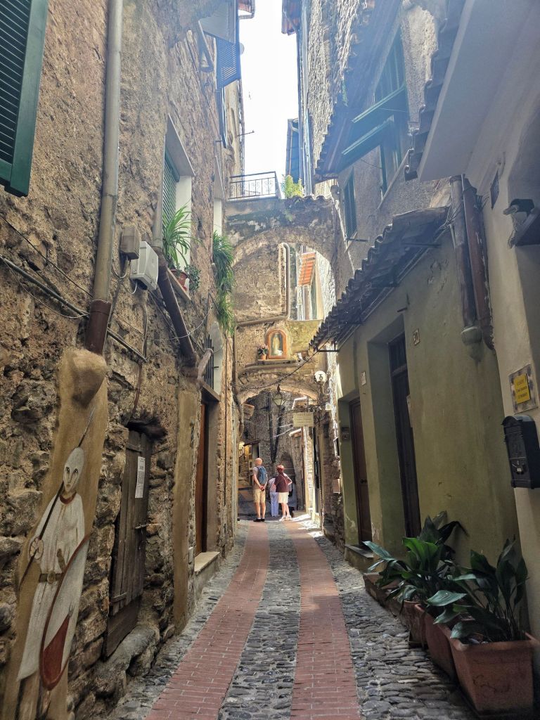 In this travel article I write about Dolceacqua, a picturesque, enchanting town located in the hinterland of Liguria. The photo shows a charming alley.